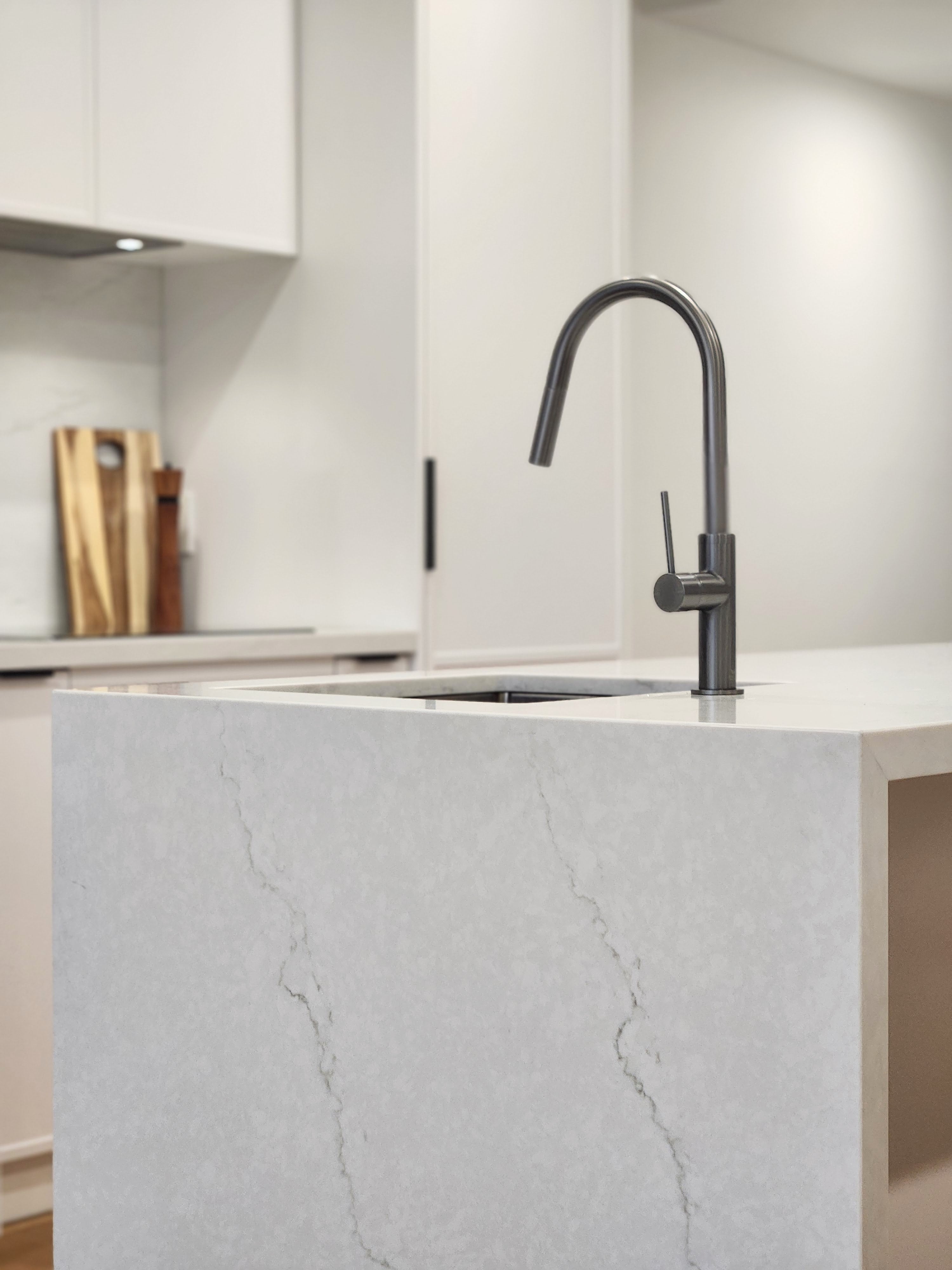 a gun metal kitchen tap on a waterfall edge grey stone benchtop