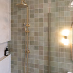brushed gold twin round combination shower rail with diverter on a green feature tile background in a modern bathroom