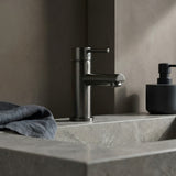 Gun Metal Basin Mixer with Round Spout on a marbel sink with a neutral background
