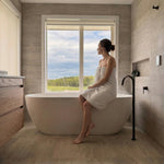 A lifestyle photo showing the antique brass floor spout over a bath overlooking the garden. 
