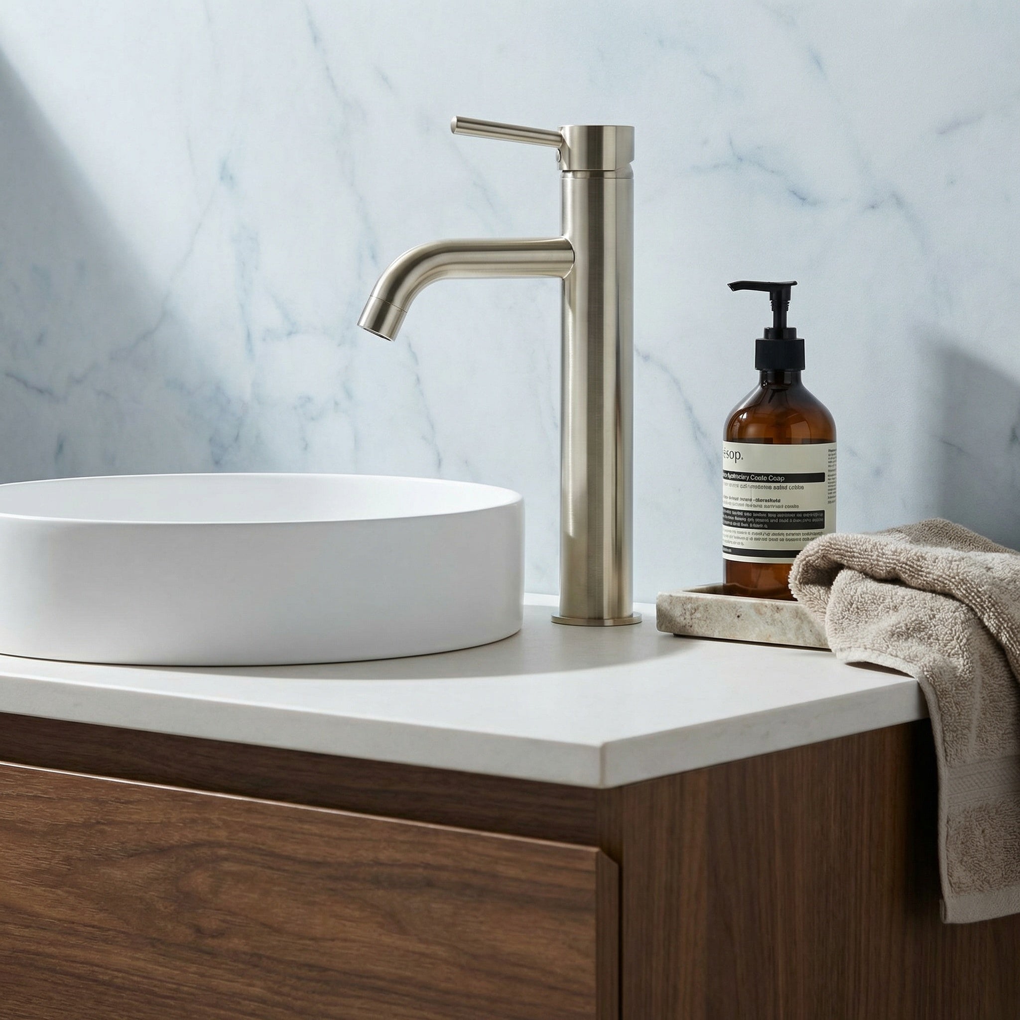 Our tall basin mixer in brushed nickel pictured with white sink, timber cabinetry with a marble wall 