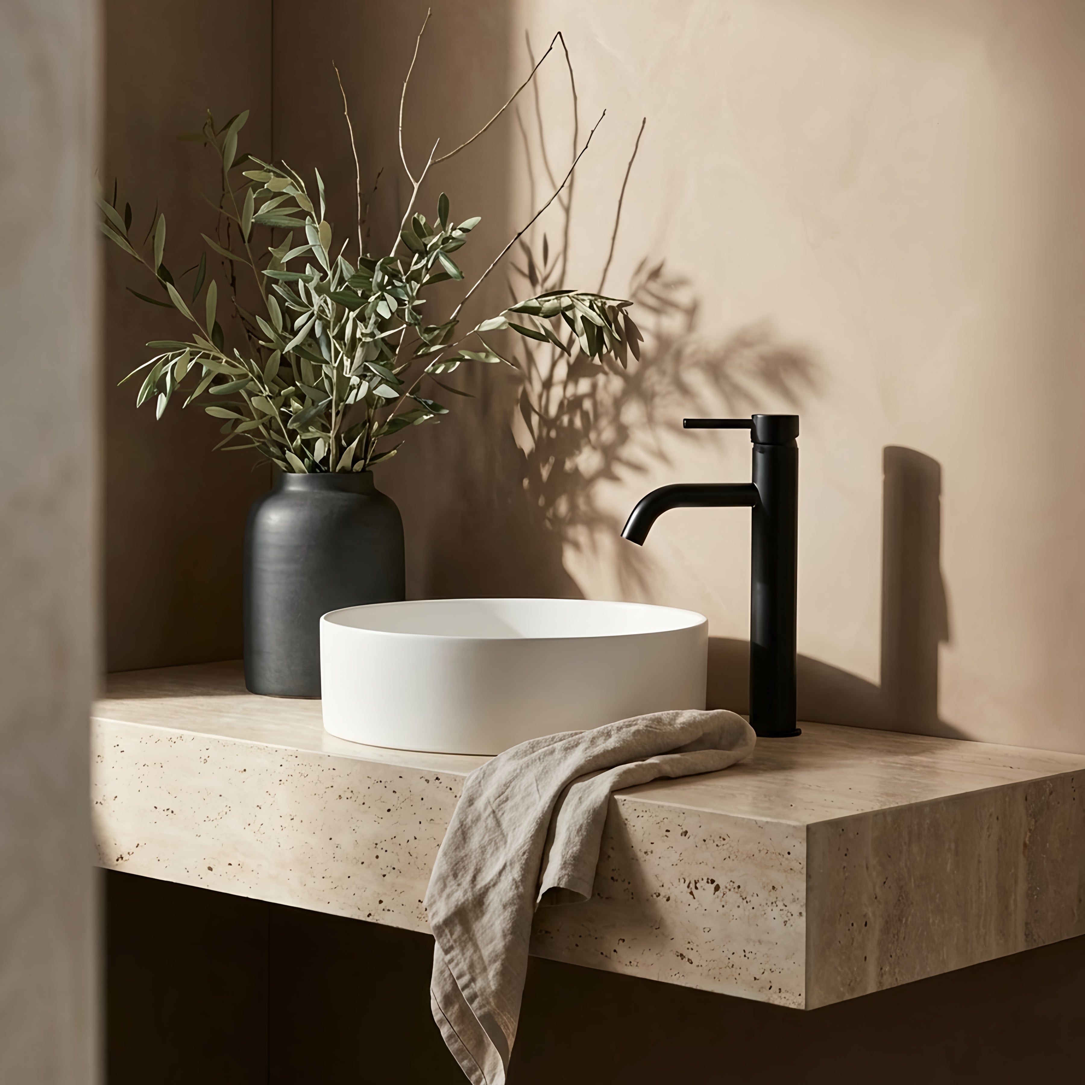 Bathroom vanity with white sink, matt black tall basin mixer, and vase with olive branches