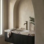 Notorious Tall Basin Mixer Antique Brass shown in a modern bathroom setting with a marble vanity top