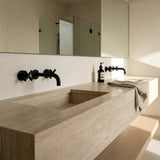 Modern bathroom with concrete sink with matt black cross handle taps with wall spout