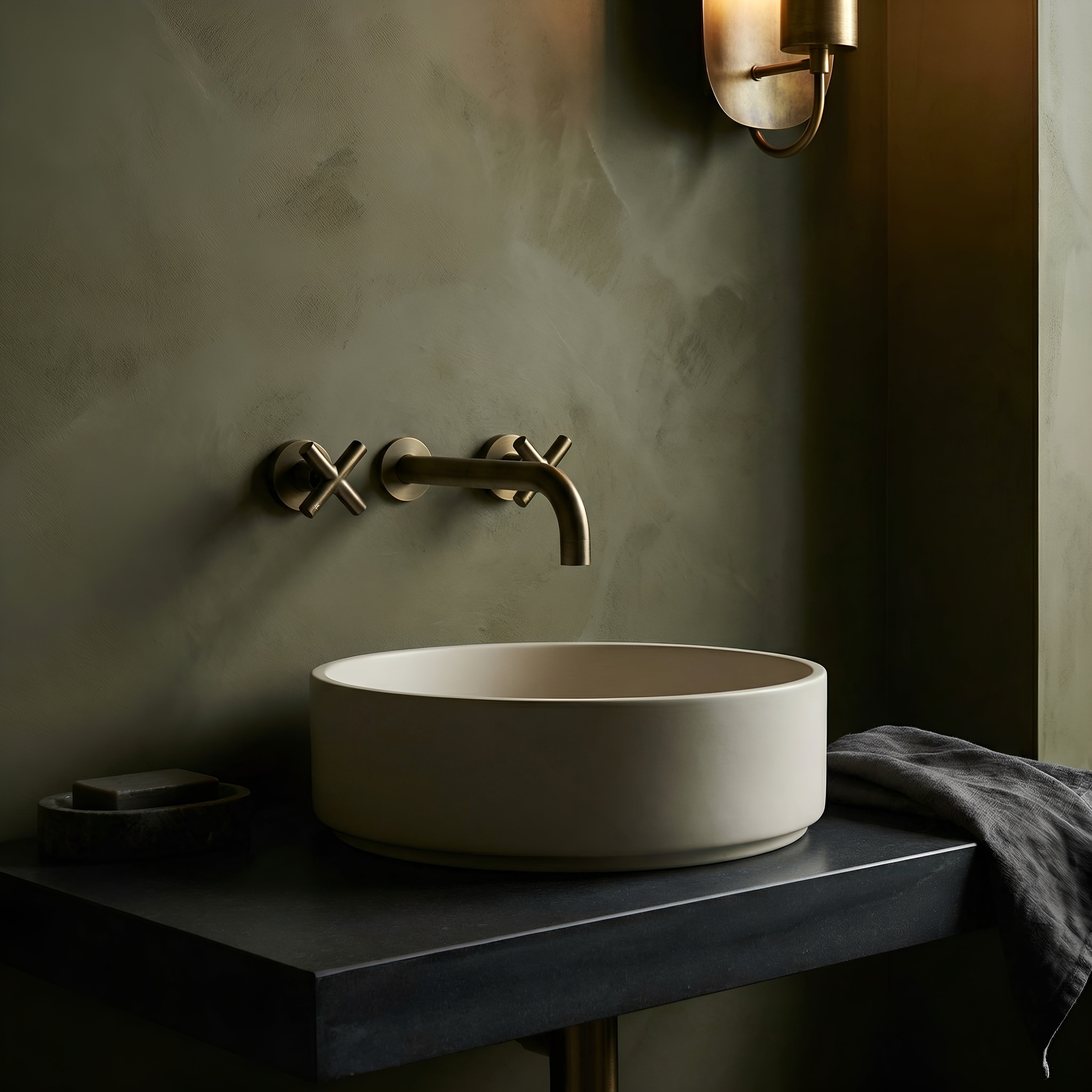 Bathroom sink with antique bronze cross handle taps and wall spout against a green wall