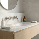 Bathroom vanity with brushed nickel cross handle taps and wall spout, mirror, and toiletries