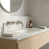 Bathroom vanity with brushed nickel cross handle taps and wall spout, mirror, and toiletries