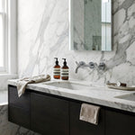 Bathroom vanity with marble countertop, dark cabinets, with Chrome cross handle taps and wall spout