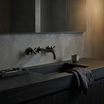 Modern bathroom sink with dark countertop and gun metal cross handle taps with wall spout