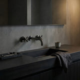 Modern bathroom sink with dark countertop and gun metal cross handle taps with wall spout