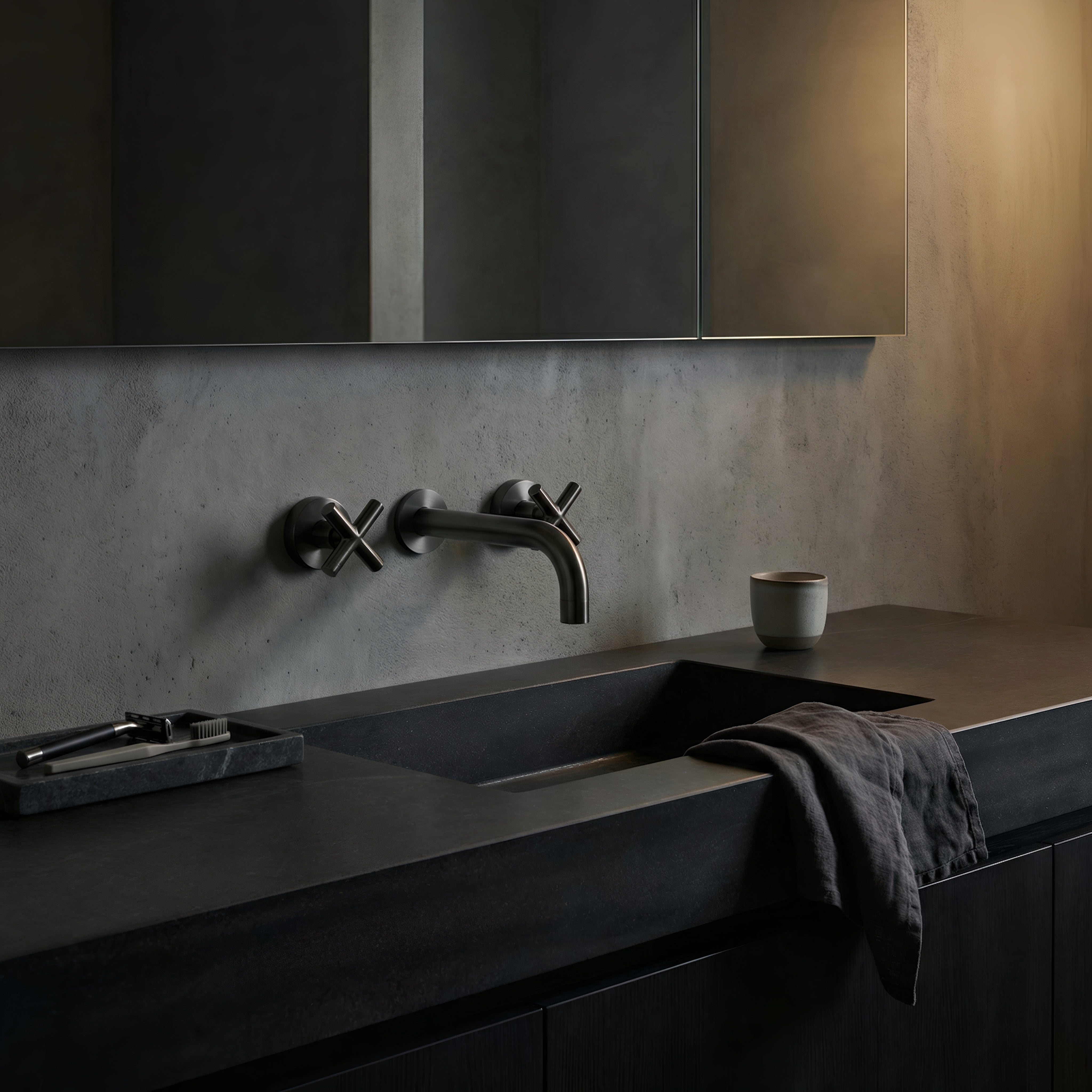 Modern bathroom sink with dark countertop and gun metal cross handle taps with wall spout