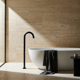 Modern bathroom with a white freestanding bathtub, black floor spout, and beige tiled wall.