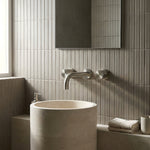 Modern bathroom with a freestanding sink and tiled walls with brushed nickel round wall taps and wall spout.