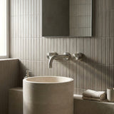 Modern bathroom with a freestanding sink and tiled walls with brushed nickel round wall taps and wall spout.