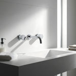 Modern bathroom sink with chrome round wall taps with wall spout on a white countertop.