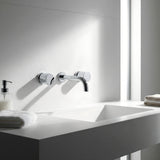 Modern bathroom sink with chrome round wall taps with wall spout on a white countertop.