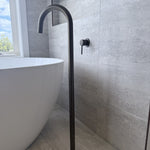 Bathroom setting with a freestanding bathtub and antique brass floor bath spout.