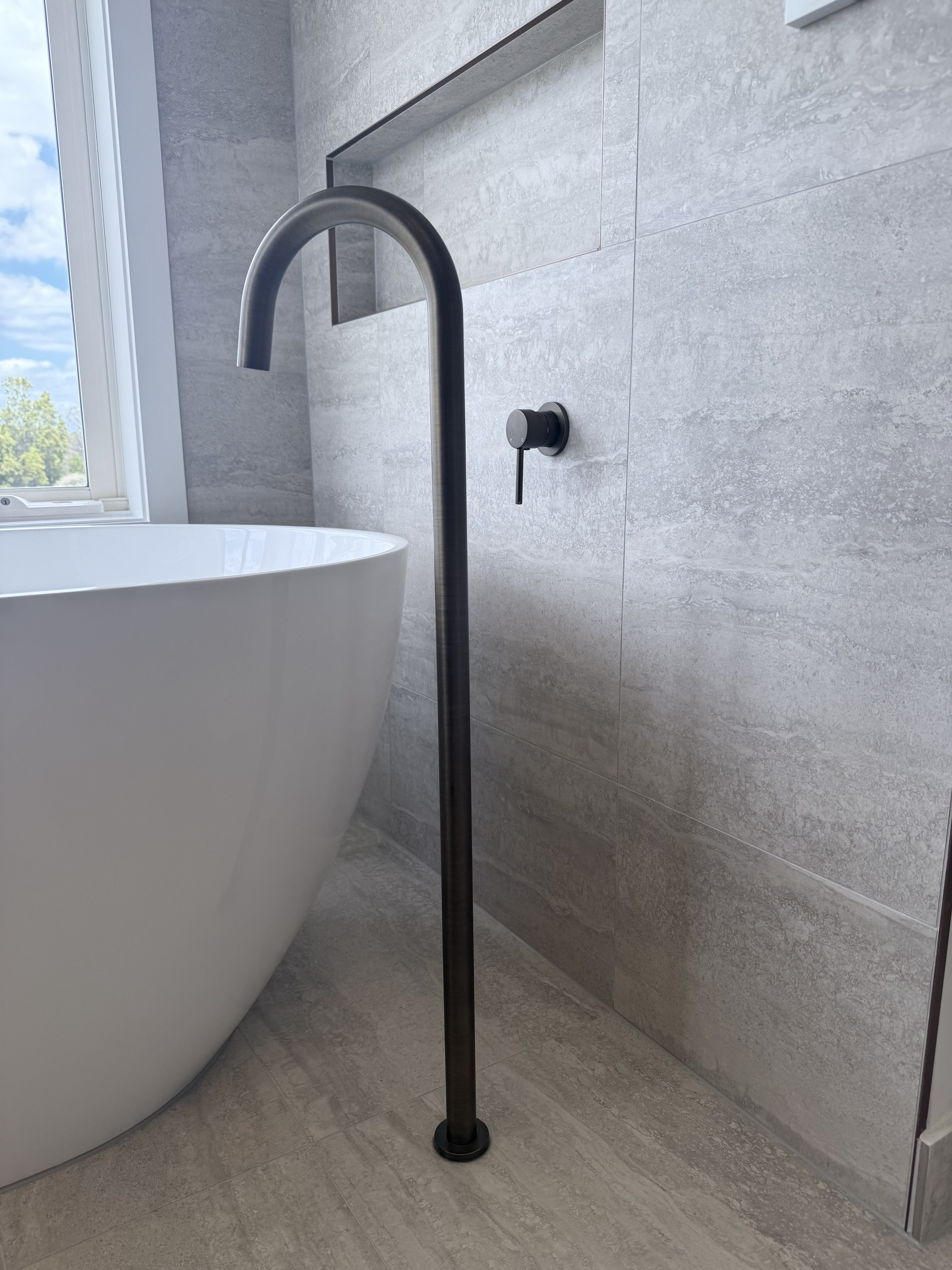 Bathroom setting with a freestanding bathtub and antique brass floor bath spout.