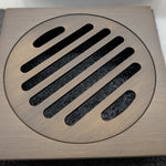 Antique brass floor grate cover with slotted design on a textured surface