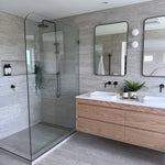 Antique Brass tapware in a modern bathroom with glass shower enclosure, wooden vanity, and large mirror.