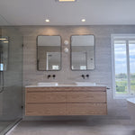 Modern bathroom with wooden vanity, mirrors, and a bathtub.