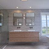 Modern bathroom with wooden vanity, mirrors, and a bathtub.
