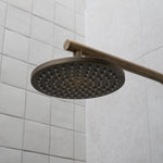 an antique brass shower head mounted on a tiled wall