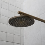 an antique brass shower head mounted on a tiled wall