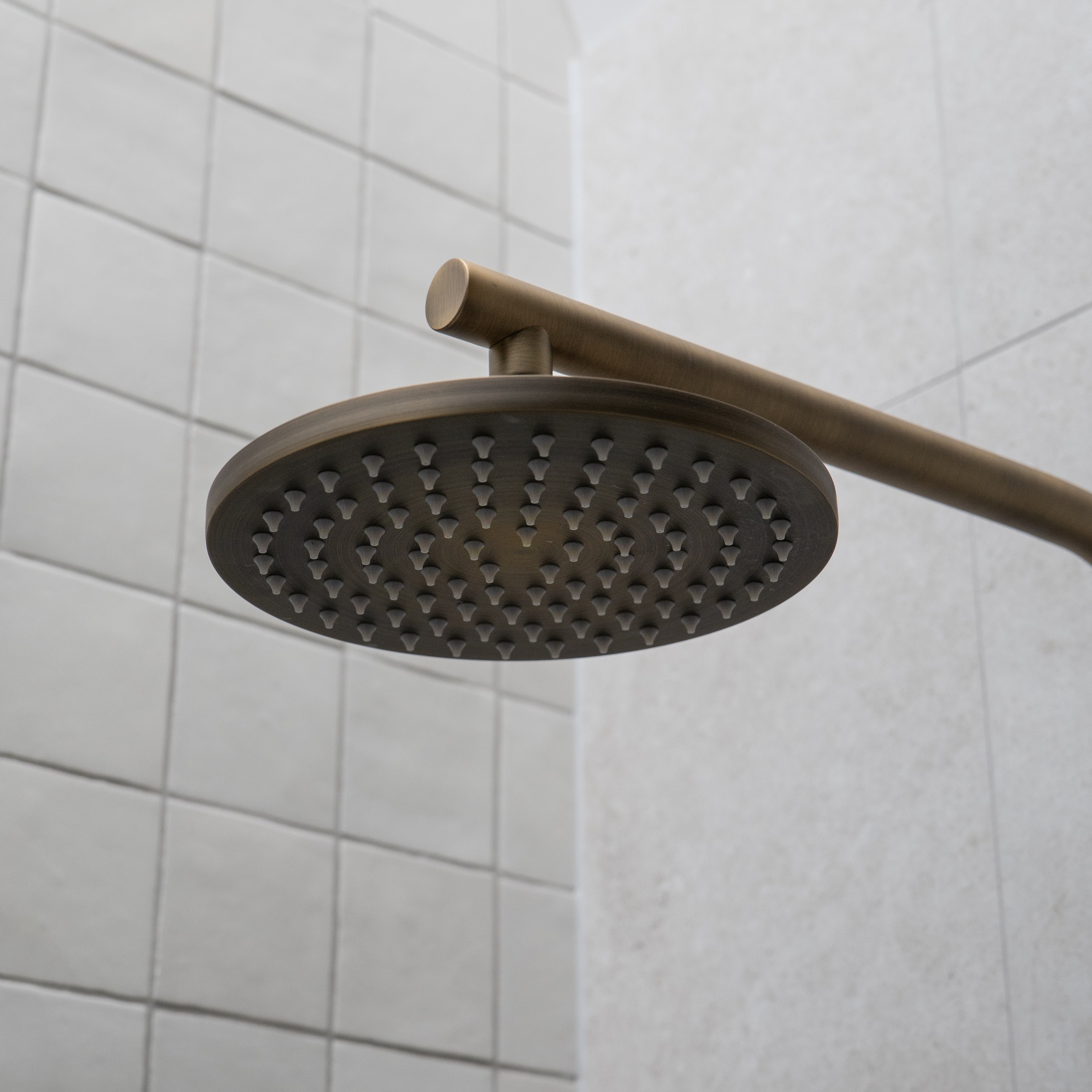 an antique brass shower head mounted on a tiled wall
