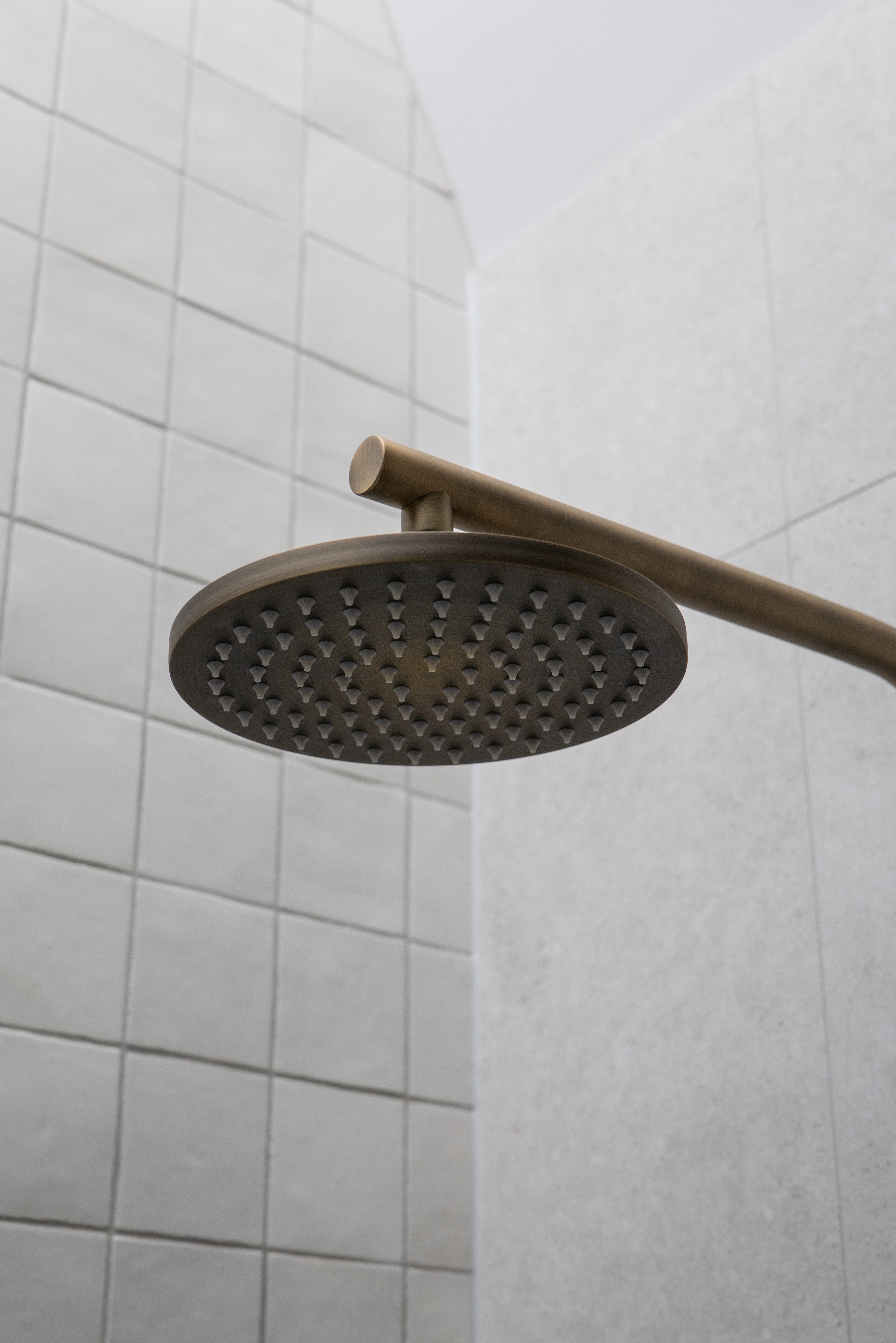 an antique brass shower head mounted on a tiled wall