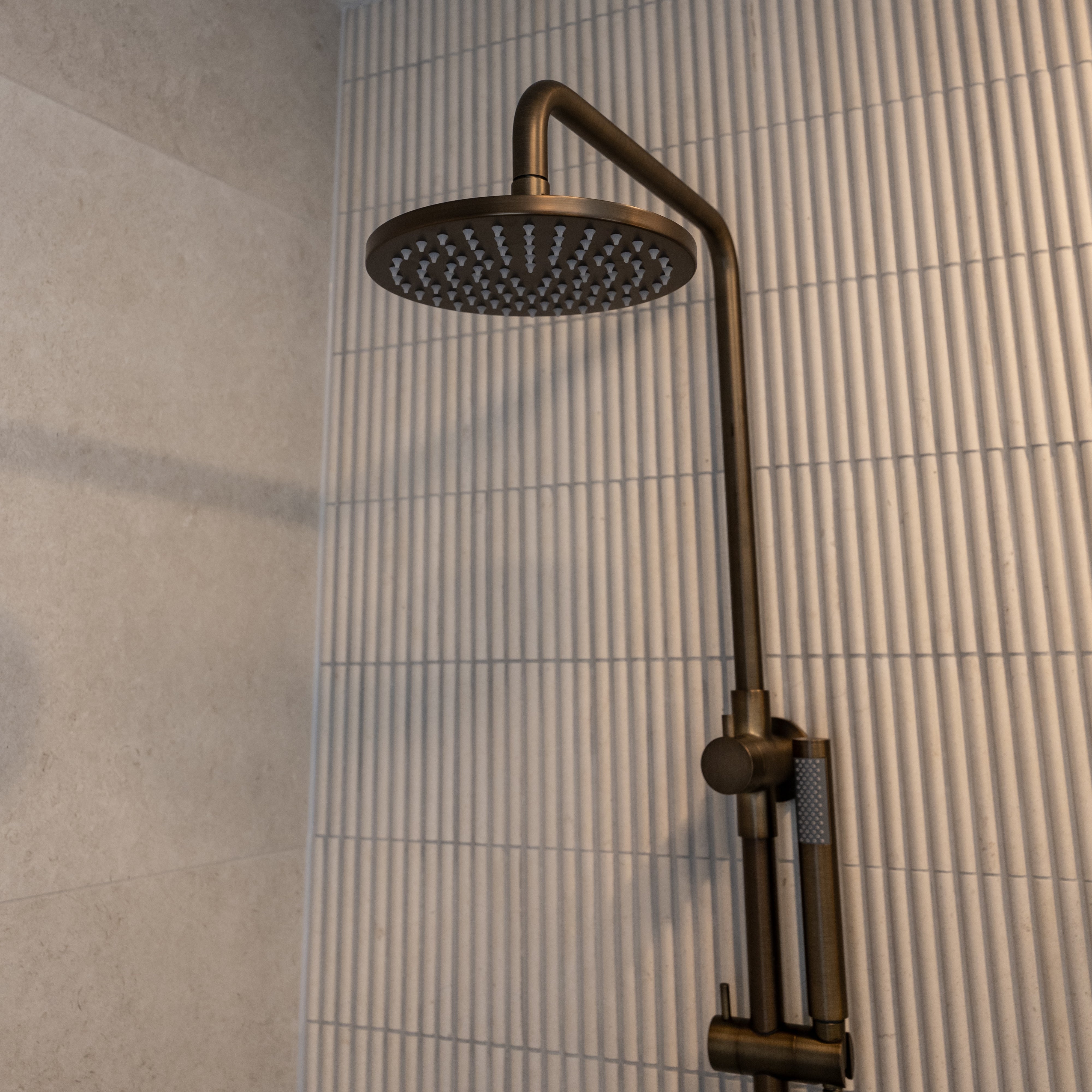 Antique brass twin shower with diverter on a tiled bathroom wall