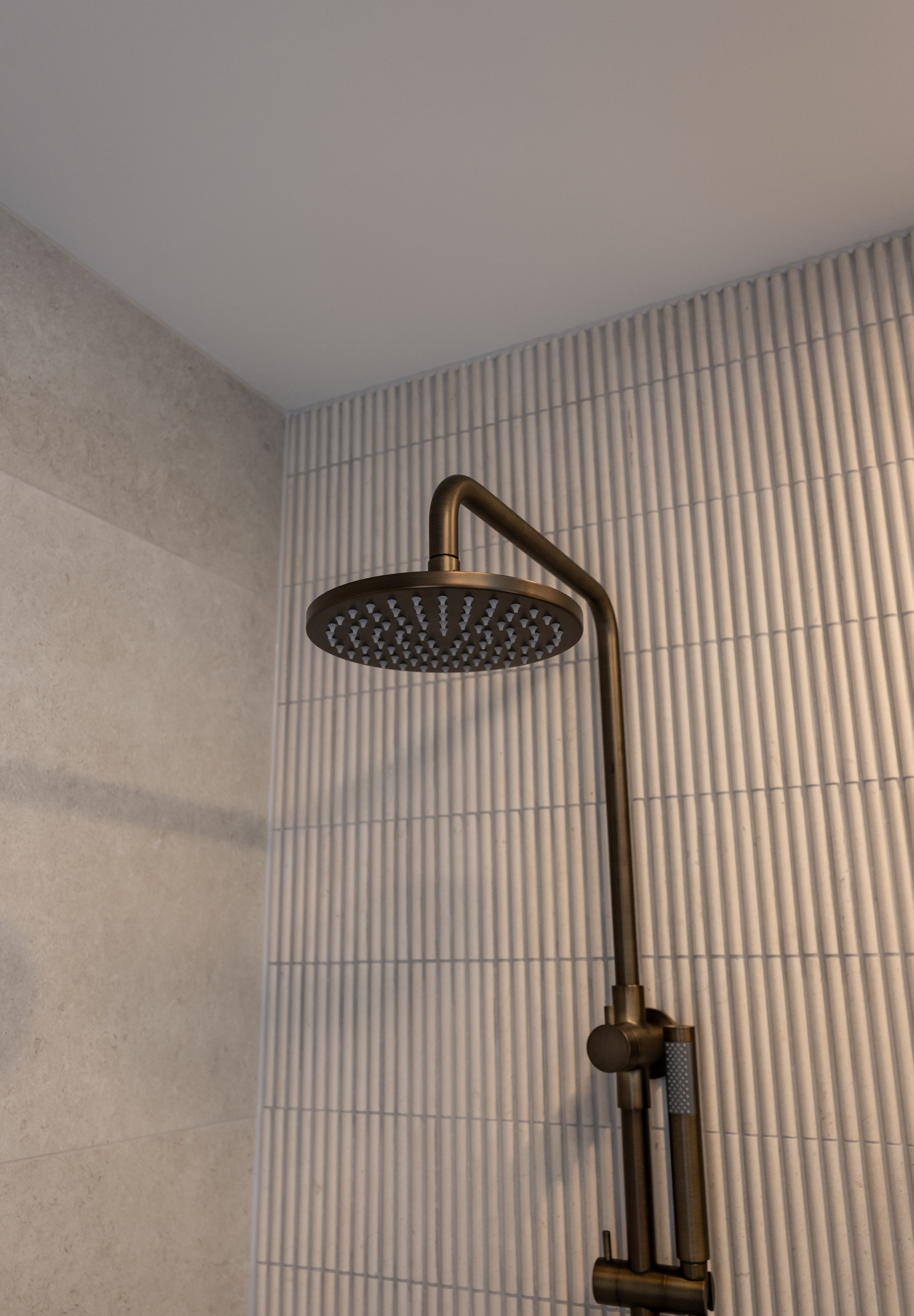 Antique brass twin shower with diverter on a tiled bathroom wall