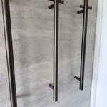 Set of antique brass single bar heated towel rails on a grey tiled wall