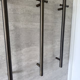 Set of antique brass single bar heated towel rails on a grey tiled wall