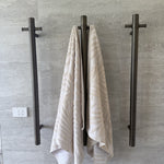 Towel hanging on a antique brass single bar heated towel rail against a tiled wall