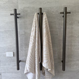 Towel hanging on a antique brass single bar heated towel rail against a tiled wall