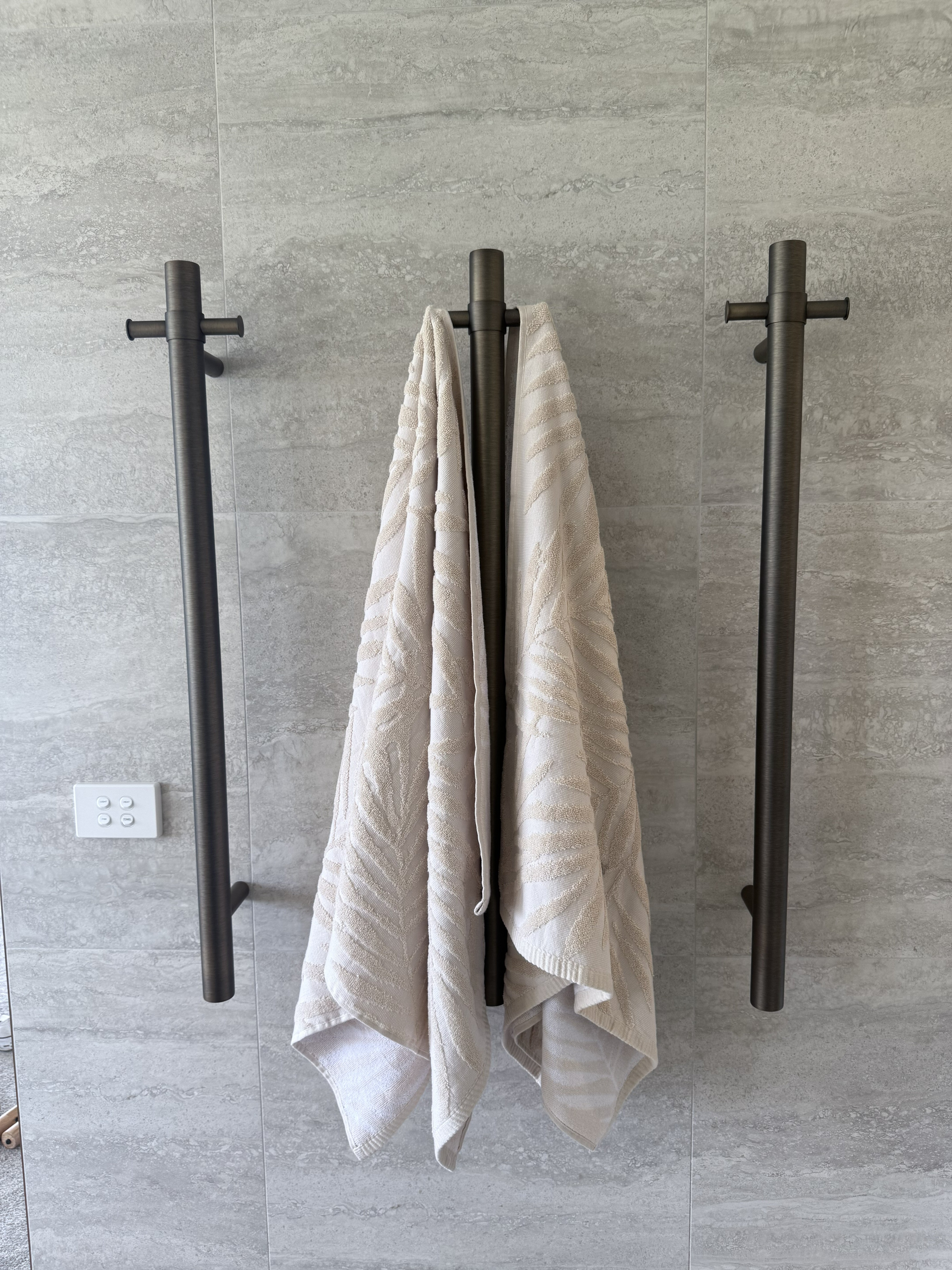Towel hanging on a antique brass single bar heated towel rail against a tiled wall