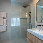 Modern bathroom with antique brass twin shower with diverter, sink, and white heated towel rails