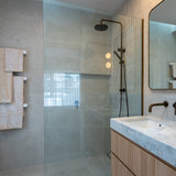Modern bathroom with antique brass twin shower with diverter, sink, and white heated towel rails