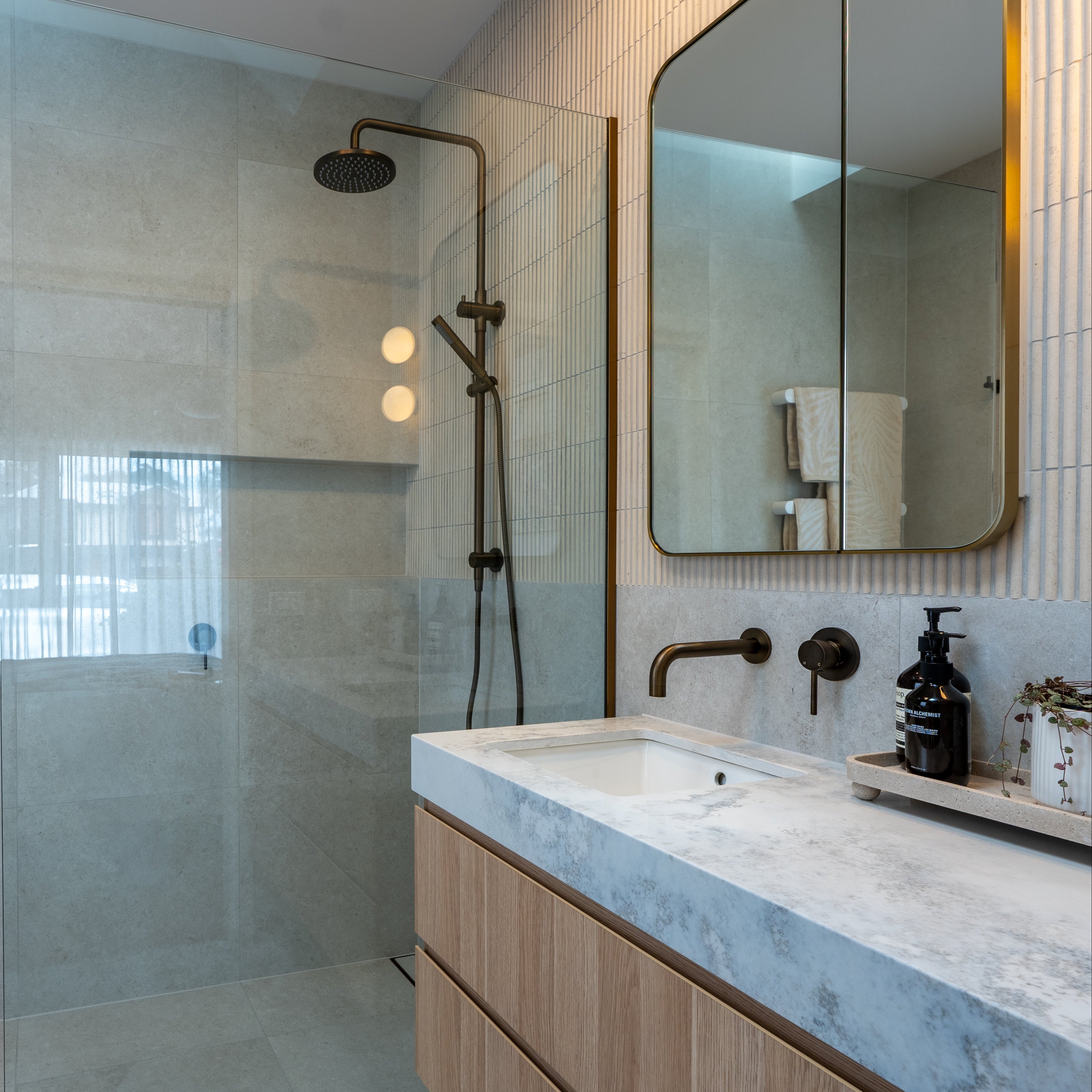 Modern bathroom with antique brass twin shower with diverter, sink, and white heated towel rails