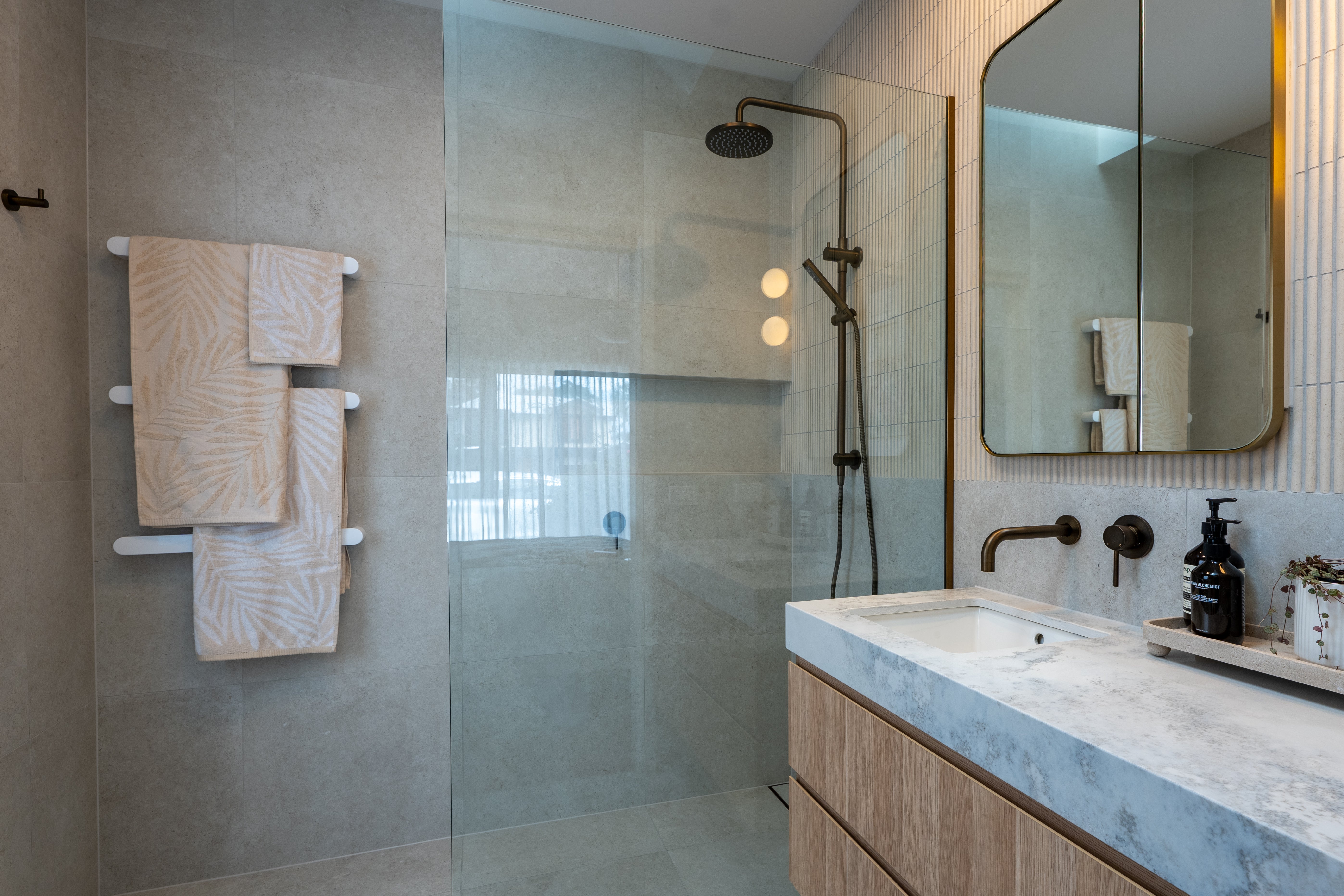 Modern bathroom with antique brass twin shower with diverter, sink, and white heated towel rails