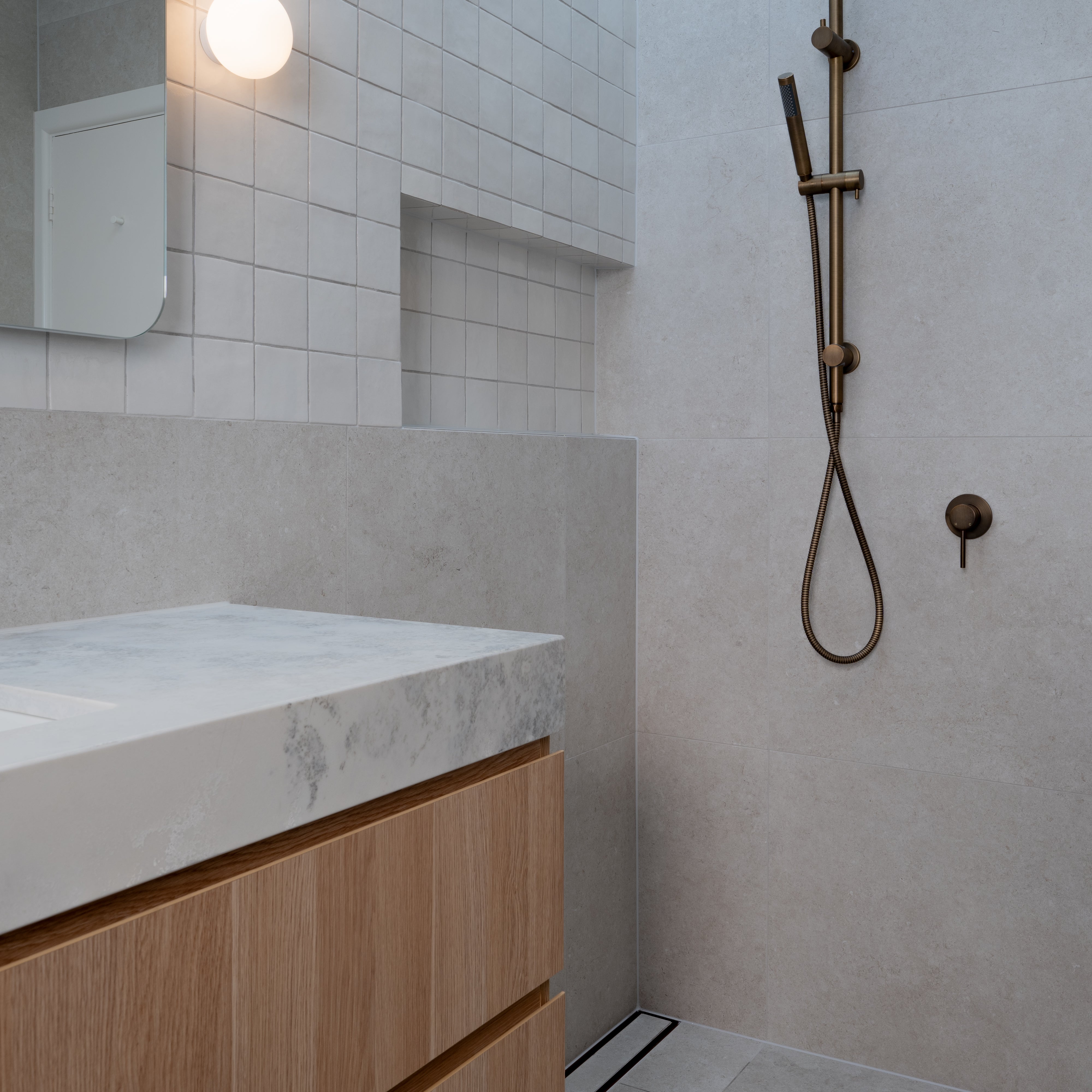 Antique Brass Twin Round Combination Shower Rail with Diverter and Hand Held wand on a grey tile background
