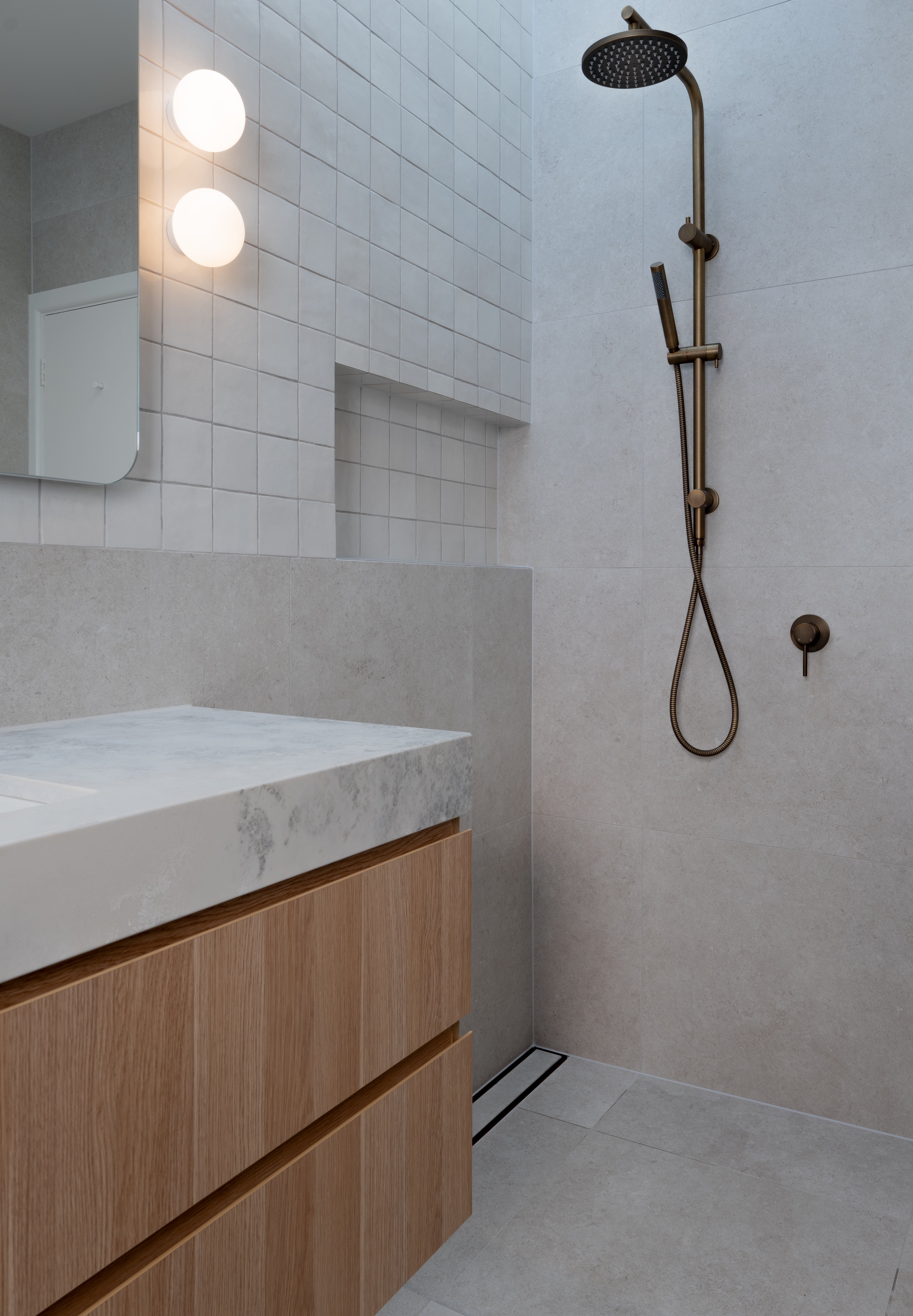 Antique Brass Twin Round Combination Shower Rail with Diverter and Hand Held wand on a grey tile background