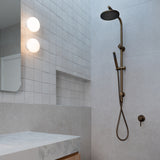 Antique Brass Twin Round Combination Shower Rail with Diverter and Hand Held wand on a grey tile background