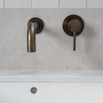 antique brass wall mounted over vanity wall mixer and spout on grey and white tile background