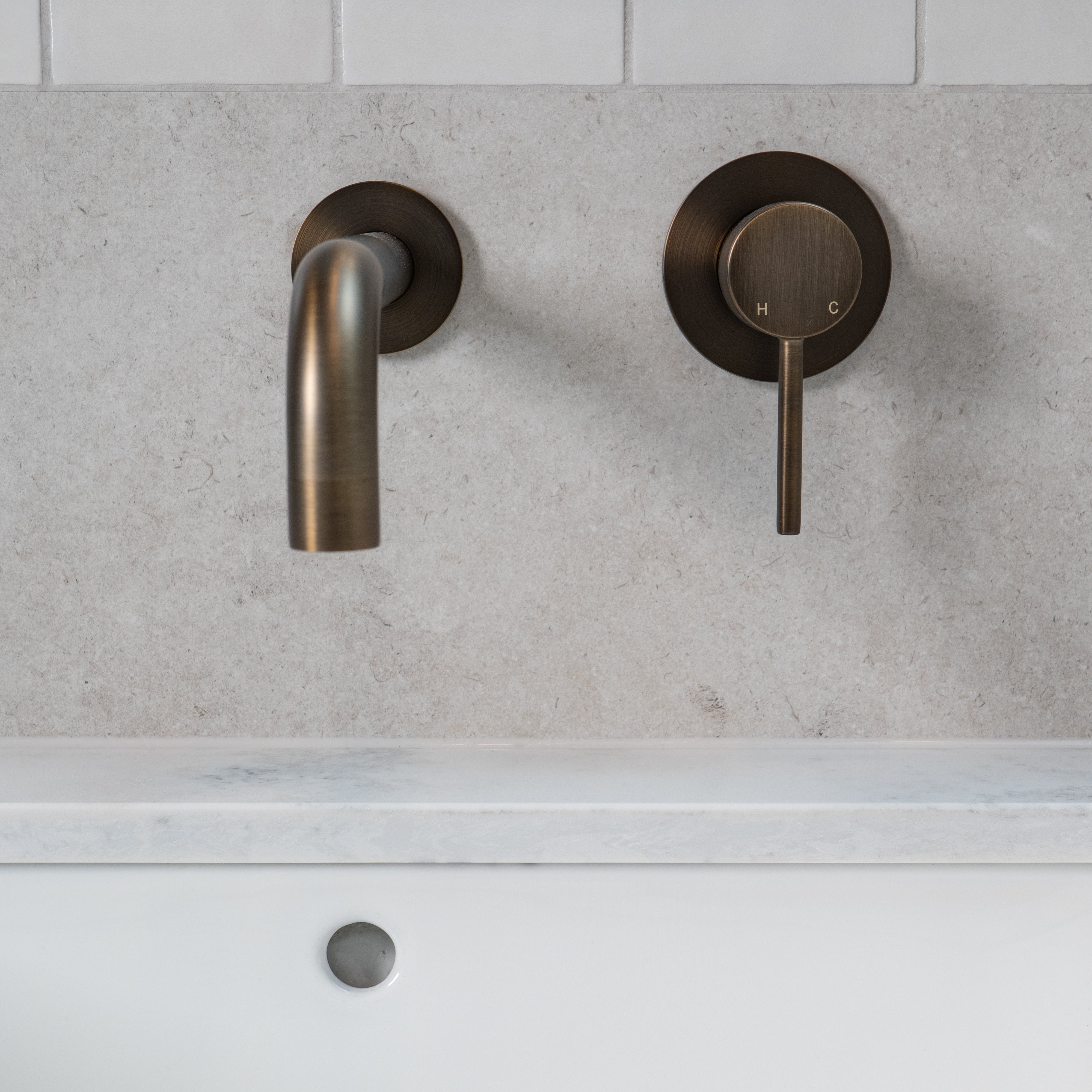 antique brass wall mounted over vanity wall mixer and spout on grey and white tile background