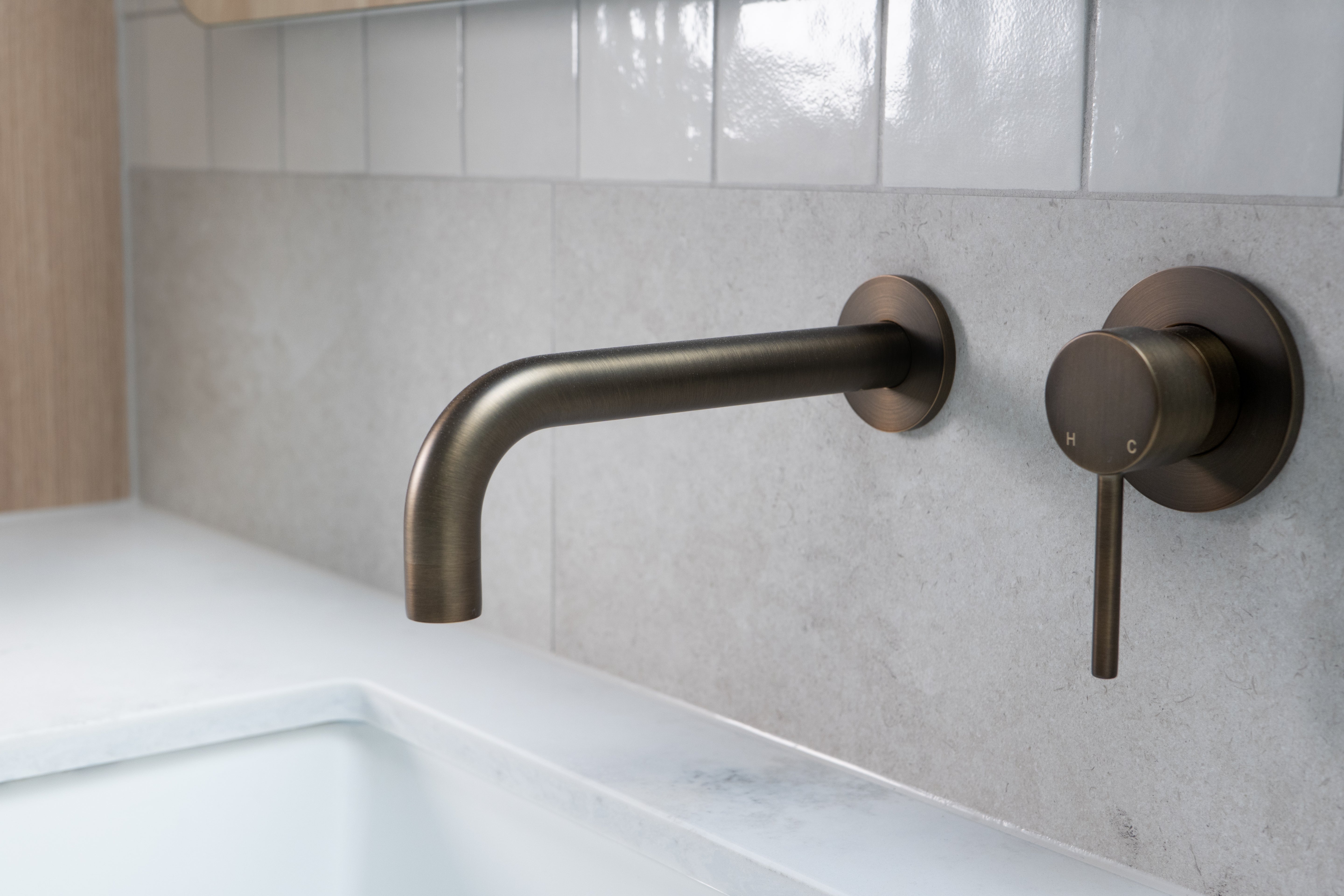 Antique Brass tap wall spout and mixer on grey tile marble bench and white tile splash back