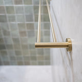 A brushed gold double towel rail wall mounted on a tile wall