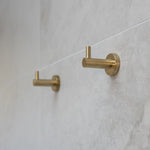 Brush gold robe hooks on a tiled wall