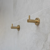 Brush gold robe hooks on a tiled wall
